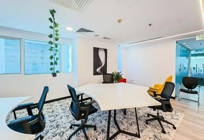 Meeting area with a uniquely shaped white table, black chairs, and hanging greenery.