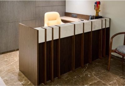 Modern reception area with a dark wood and white marble front desk and marble flooring.