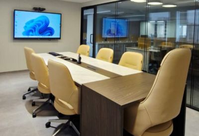 Professional meeting room with a long conference table, yellow chairs, and a large wall-mounted screen.