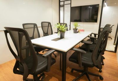 Modern boardroom featuring a white table, mesh chairs, and a large wall-mounted monitor.