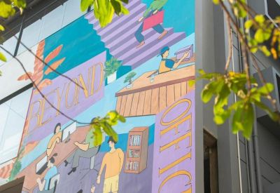 Exterior mural on the Kanak Swaroop Building with vibrant illustrations and building signage.