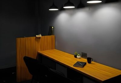 Close-up of a wooden workstation with black pendant lamps and warm ambient lighting.
