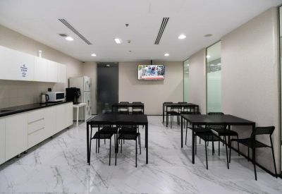 Staff breakroom with sleek black dining tables and a wall-mounted television.