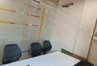 Small meeting room with a white table, mesh chairs, and a glass partition.