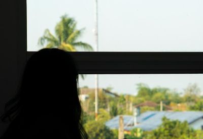 Silhouette of a person working by a window with views of a palm tree and distant tower.