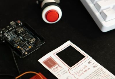 Close-up of a workstation with a mechanical keyboard, circuit board, and arcade-style button.