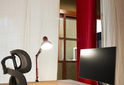 Private L-shaped wooden desk under a white and red fabric canopy with an ergonomic chair.