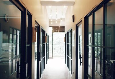 Long hallway with glass-walled offices and hanging light bulbs.