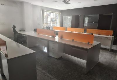 Coworking area with rows of workstations and ergonomic black mesh chairs.