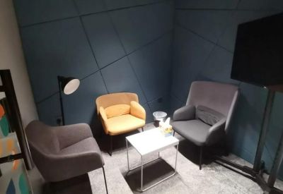 A colorful meeting room at Dan Plaza, Makkah with a feature wall and plush yellow and grey armchairs.