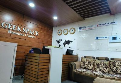 Wood-paneled reception area at Geek Space Business Centre with comfortable seating and world map wall art.