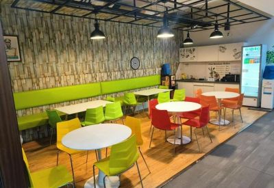 Colorful communal break area with lime green booths, red chairs, and a white round table.