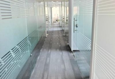 Bright corridor with frosted glass partitions and striped patterns leading to private offices.