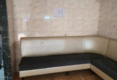 L-shaped cream and black cushioned sofa against a tiled wall in a reception area.