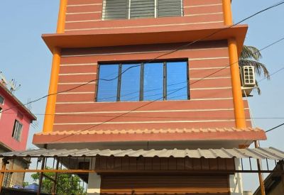 Exterior view of the three-story orange and brown building at Ganeshpur Road with a storefront entrance.