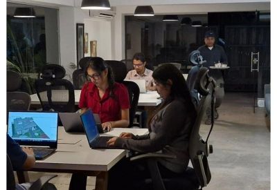 Modern open-plan office with employees working at white desks under industrial pendant lighting.