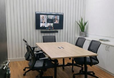 Meeting room with wood-topped table, video conferencing screen, and vertical slat feature wall.