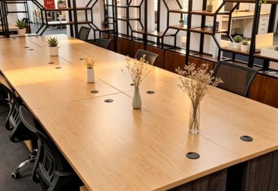 Long wooden coworking table with small potted plants and dried floral vases.