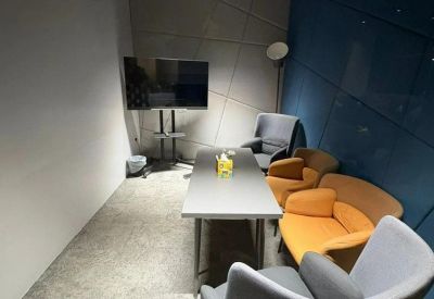 Meeting room at King Abdul Aziz Branch Road with a long table, orange armchairs, and a wall-mounted TV.
