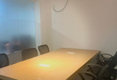 Minimalist meeting room with a light wood table and ergonomic black chairs.