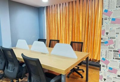 Spacious co-working table with privacy dividers and vibrant orange curtains.