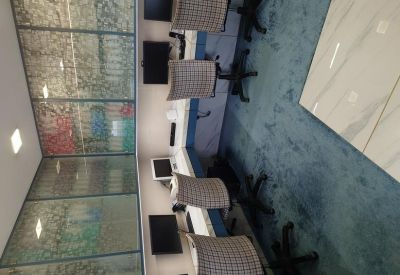 Close-up of a workstation setup with a patterned office chair and glass-paneled wall.