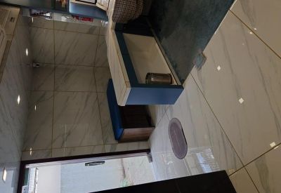 A clean office hallway with marble finishes and a blue reception desk area.