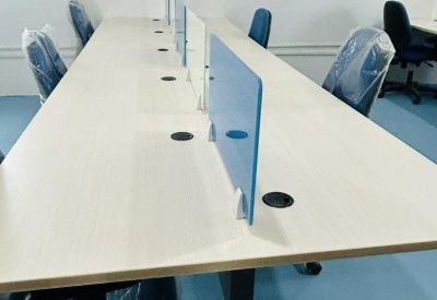Long workstation table with blue privacy dividers and integrated cable management.
