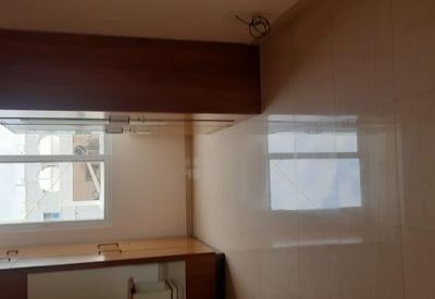 A modern kitchen area featuring white cabinetry and a window overlooking the street.