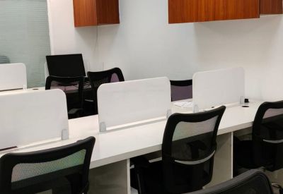 Open-plan office area with white desks, privacy partitions, and black ergonomic chairs.