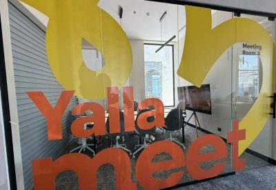 Modern meeting room seen through glass doors with bold yellow and orange vinyl lettering.
