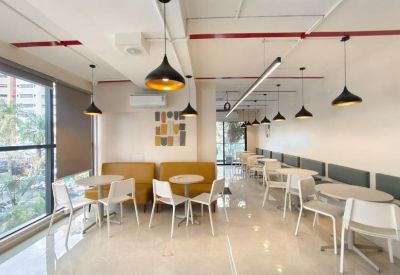 Bright communal lounge and cafe area with yellow sofas and pendant lighting.