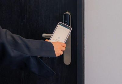 Hand with smartphone unlocking door via smart lock.