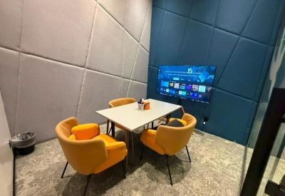 Private meeting room at Prince Sultan Road with yellow armchairs and a wall-mounted TV.