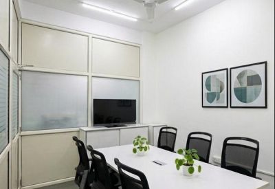 Bright conference room with a white table, six black chairs, and a wall-mounted television.