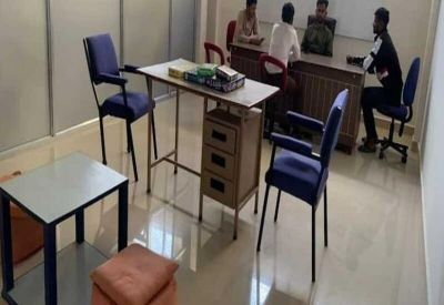Meeting room with several people seated around a large desk and a whiteboard.