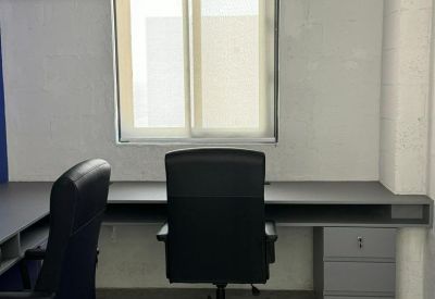 Double workstation desk against a white wall with a high-back ergonomic chair.