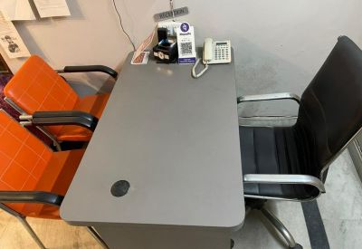Compact grey desk with an orange guest chair and black office chair.