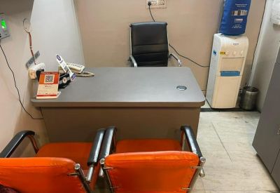 Office workspace featuring a grey desk, orange guest chairs, and a water cooler.