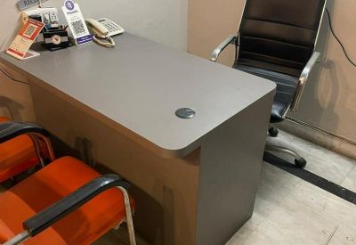 Desk setup with a black leather chair and a grey workstation surface.