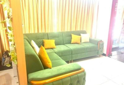 L-shaped green velvet sofa with yellow accent pillows in a lounge area.