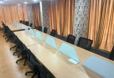 Long coworking table with white privacy dividers and ergonomic chairs.