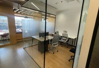 A bright private office suite with glass walls and multiple workstations.