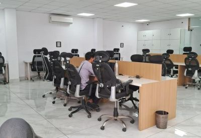 Open-plan office with a person working at a desk and several empty workstations.