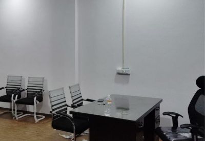 Office space with a desk and several chairs against a white wall.