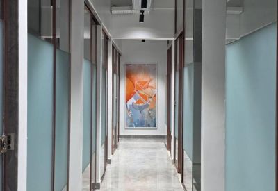 Bright hallway with glass-walled offices and colorful abstract wall art.