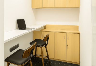 Small break area or workspace with wood-finished cabinets and high bar stools.