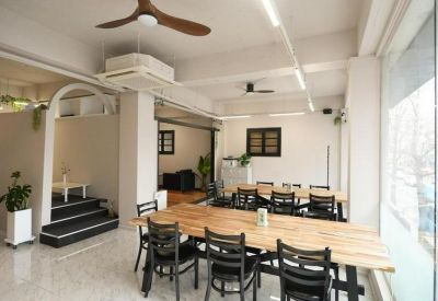 Spacious communal coworking area at suyeong ro 513 with large wooden tables, ceiling fans, and indoor plants.