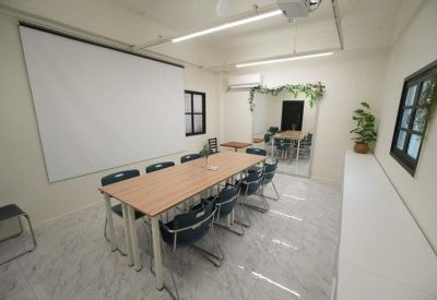 Bright meeting room featuring a long wooden table, black chairs, and a large projection screen.