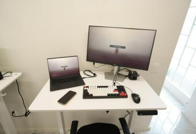 Modern white height-adjustable desk with dual monitor setup and mechanical keyboard.